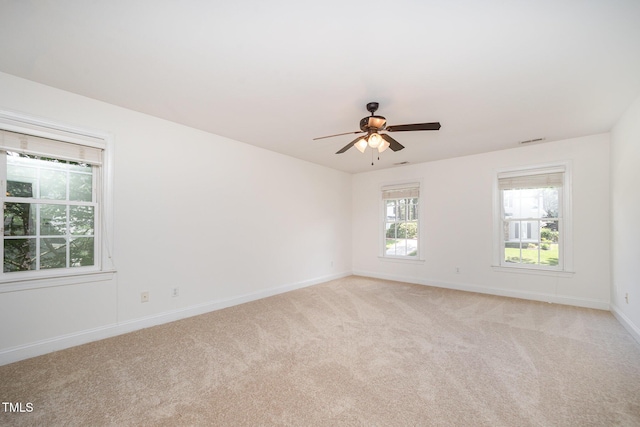 spare room with light colored carpet, ceiling fan, and baseboards