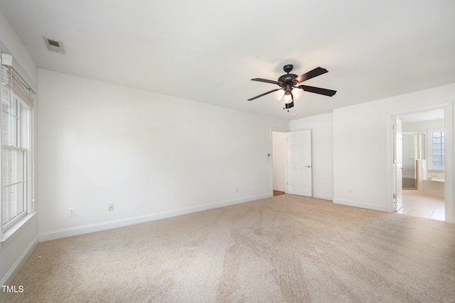 unfurnished bedroom with light colored carpet, baseboards, and ensuite bathroom