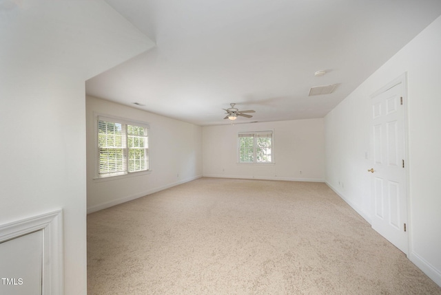 unfurnished room featuring healthy amount of natural light, ceiling fan, baseboards, and light carpet