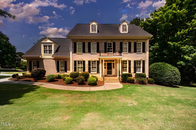 colonial house featuring a front lawn and brick siding