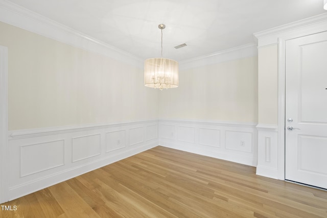 340 Allister Dr Unit 301, Raleigh, NC 27609 - unfurnished dining area featuring a chandelier, crown molding, light wood-style flooring, wainscoting, and a decorative wall