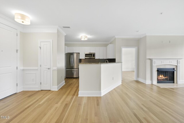 340 Allister Dr Unit 301, Raleigh, NC 27609 - kitchen featuring appliances with stainless steel finishes, white cabinets, light wood-style flooring, open floor plan, and a tile fireplace