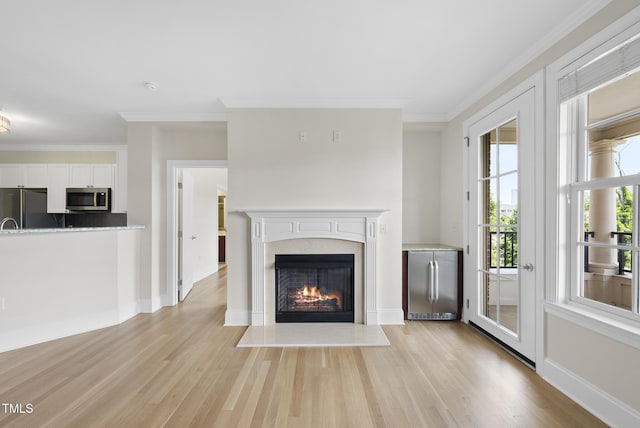 340 Allister Dr Unit 301, Raleigh, NC 27609 - unfurnished living room featuring light wood finished floors, a warm lit fireplace, crown molding, and baseboards