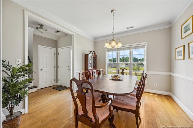 dining area featuring a chandelier, light wood-style floors, baseboards, and ornamental molding