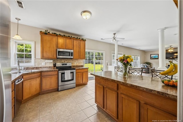 kitchen with stainless steel appliances, a sink, a ceiling fan, and decorative columns