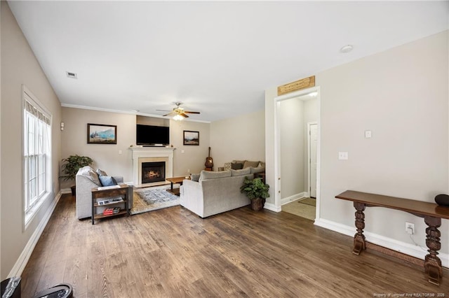 living area featuring a lit fireplace, a ceiling fan, wood finished floors, and baseboards