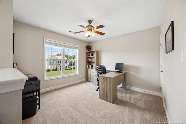 office space with a ceiling fan, baseboards, and light carpet