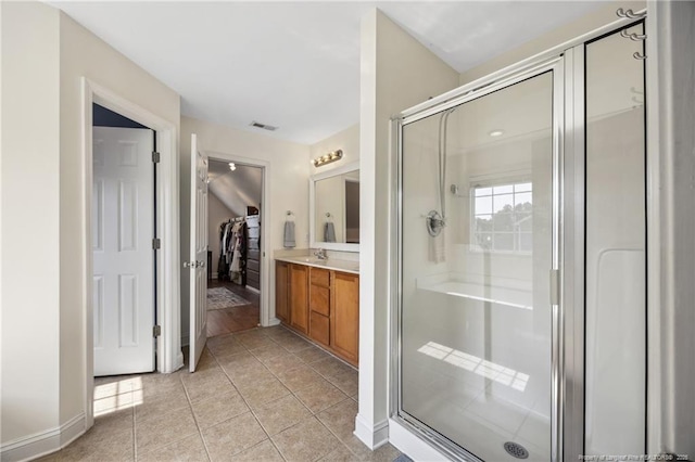 full bathroom with a shower stall, vanity, a spacious closet, and tile patterned flooring