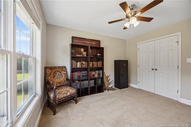 living area featuring healthy amount of natural light, carpet flooring, and ceiling fan