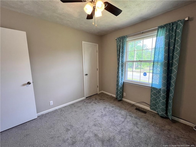 spare room featuring carpet, a textured ceiling, baseboards, and a ceiling fan