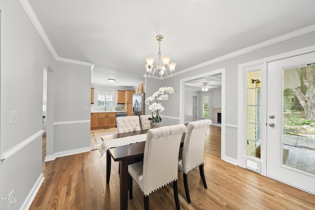 1201 Pond St, Cary, NC 27511 - dining area with a chandelier, light wood-style flooring, ornamental molding, a fireplace, and plenty of natural light