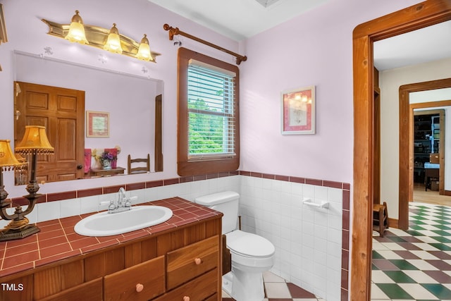 771 Cedar Grove Church Rd, Roxboro, NC 27574 - bathroom with toilet, tile patterned floors, vanity, tile walls, and a wainscoted wall