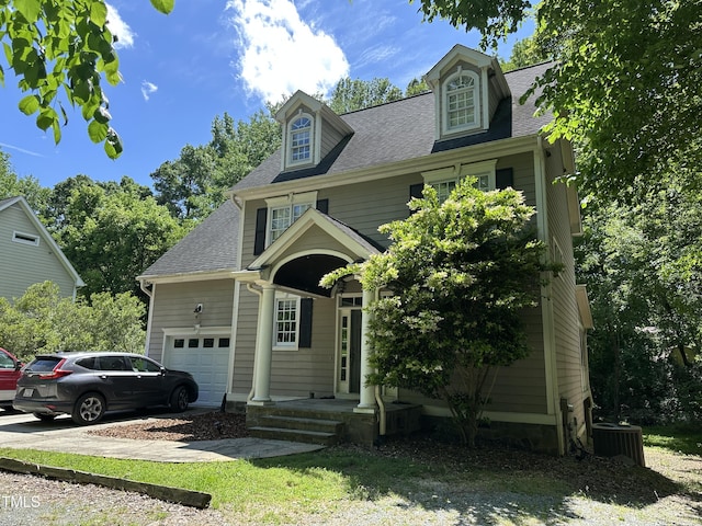 view of front of home featuring an attached garage, a shingled roof, and central AC