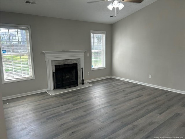 unfurnished living room with ceiling fan, dark wood-style floors, baseboards, and a fireplace