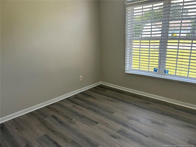 spare room with baseboards, dark wood-style floors, and plenty of natural light