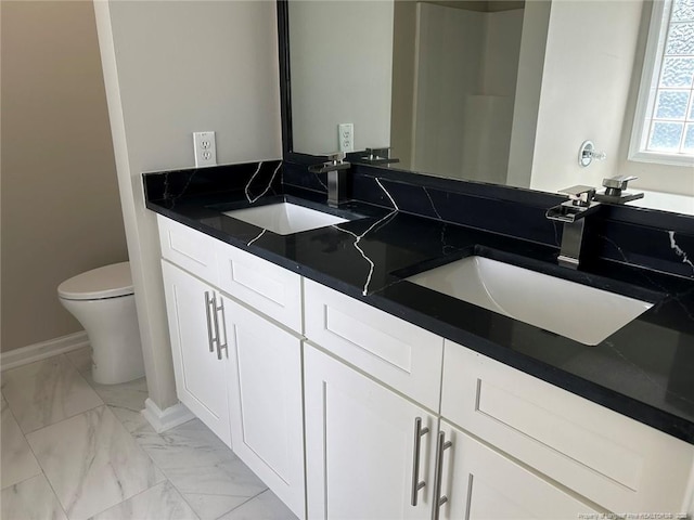 full bath featuring marble look tiles, toilet, double vanity, and baseboards