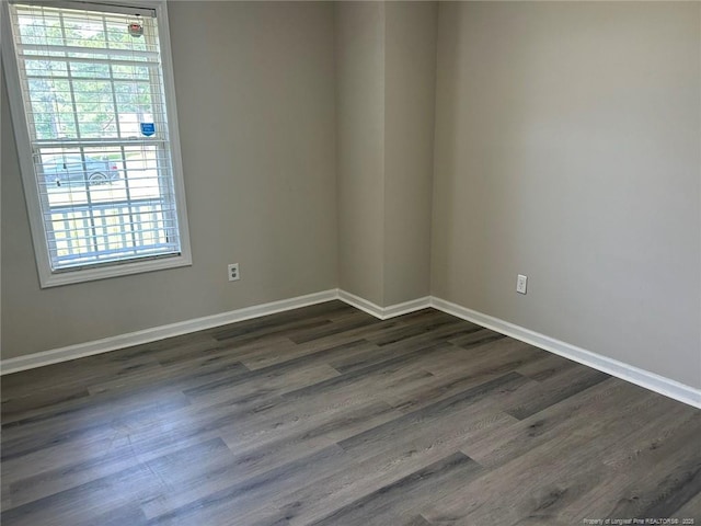 spare room with healthy amount of natural light, baseboards, and dark wood finished floors