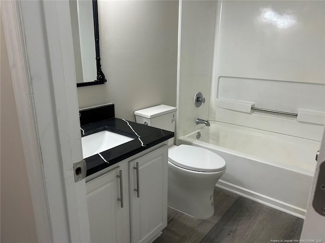 bathroom featuring wood finished floors, toilet, vanity, and bathing tub / shower combination
