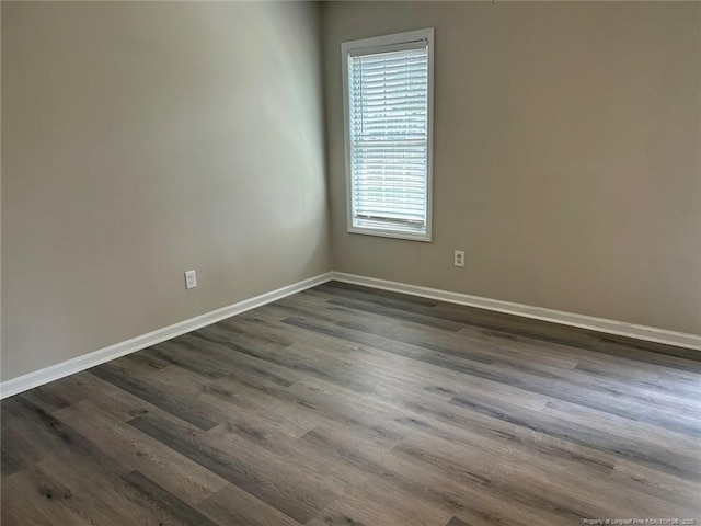 unfurnished room with baseboards and dark wood finished floors