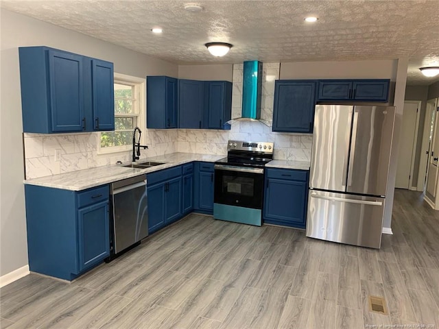 4212 Forest View Dr, Fayetteville, NC 28304 - kitchen with stainless steel appliances, wall chimney range hood, a sink, blue cabinets, and a textured ceiling