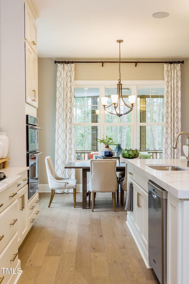 1412 Auman Rd, Raleigh, NC 27603 - kitchen with a sink, stainless steel appliances, light wood-style floors, a chandelier, and light stone counters