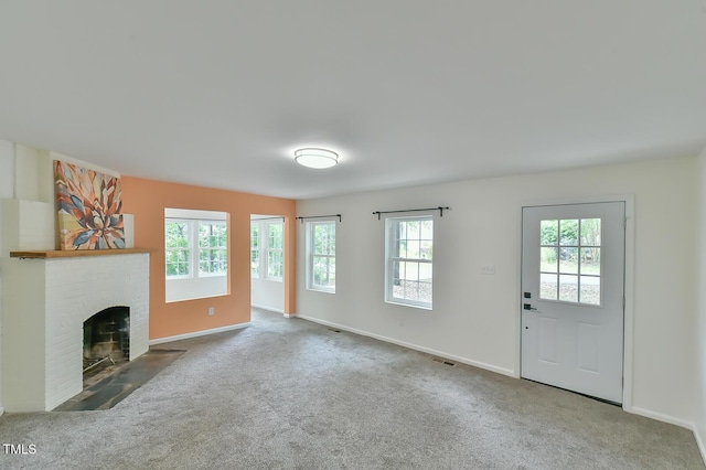 unfurnished living room featuring carpet flooring, healthy amount of natural light, a fireplace, and baseboards
