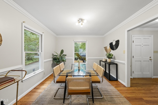 dining room with light wood-type flooring, ornamental molding, and baseboards