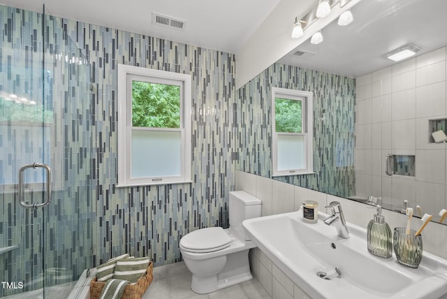 full bath featuring a sink, tile walls, a stall shower, toilet, and tile patterned flooring