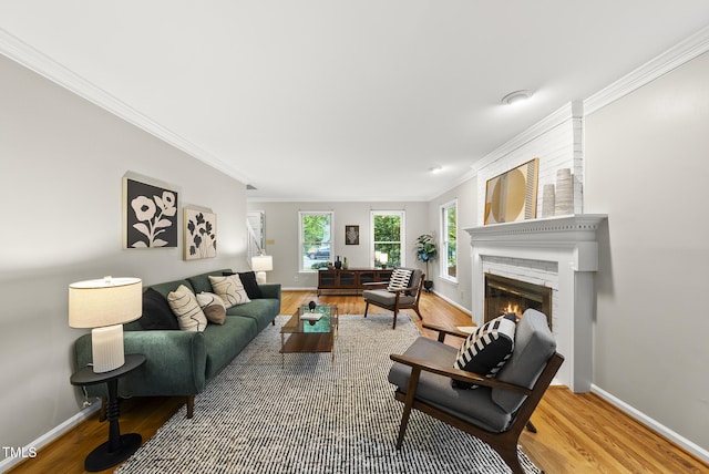 living room featuring ornamental molding, a glass covered fireplace, wood finished floors, and baseboards