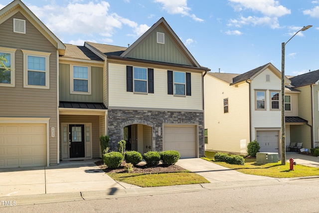 townhome / multi-family property with board and batten siding, stone siding, and concrete driveway