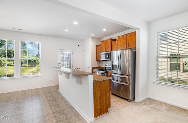kitchen with stainless steel appliances, healthy amount of natural light, light stone countertops, baseboards, and recessed lighting