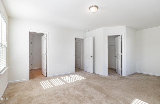 unfurnished bedroom featuring a spacious closet, multiple windows, and carpet flooring
