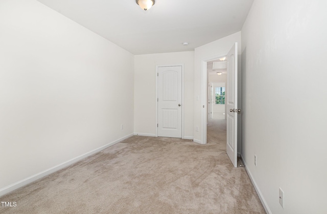 spare room with light carpet and baseboards