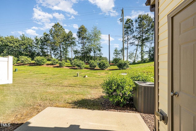 view of green lawn featuring central AC unit and a patio area