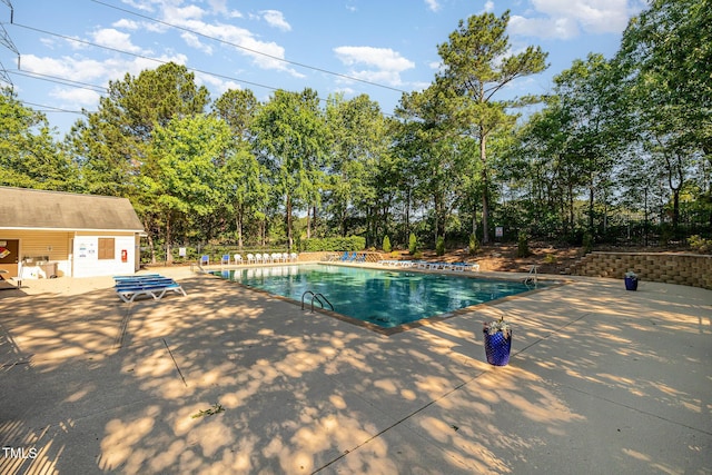 community pool featuring a patio area and view of scattered trees