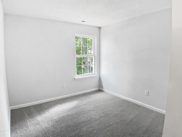 carpeted spare room featuring baseboards and a textured ceiling