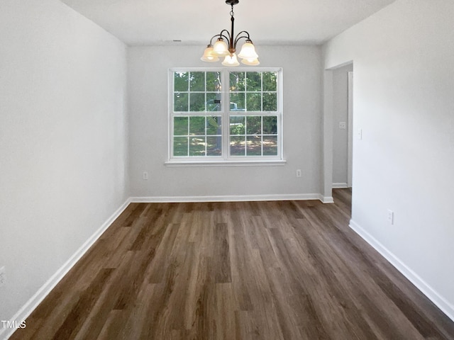 unfurnished dining area with a chandelier, dark wood-style floors, and baseboards