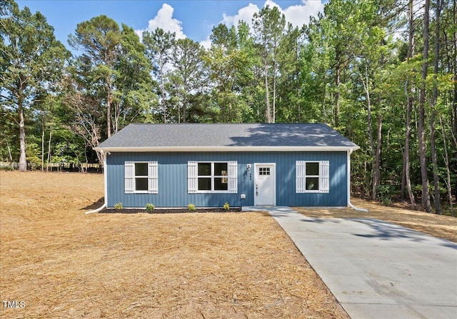 view of front of property featuring a shingled roof and concrete driveway