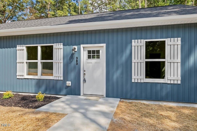doorway to property featuring roof with shingles