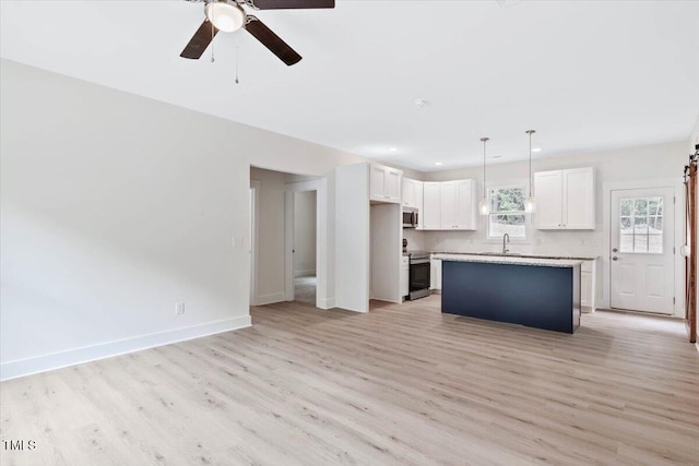 kitchen with stainless steel appliances, a sink, white cabinetry, light wood-style flooring, and a ceiling fan