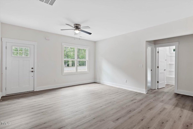 unfurnished living room with plenty of natural light, a ceiling fan, light wood-type flooring, and baseboards