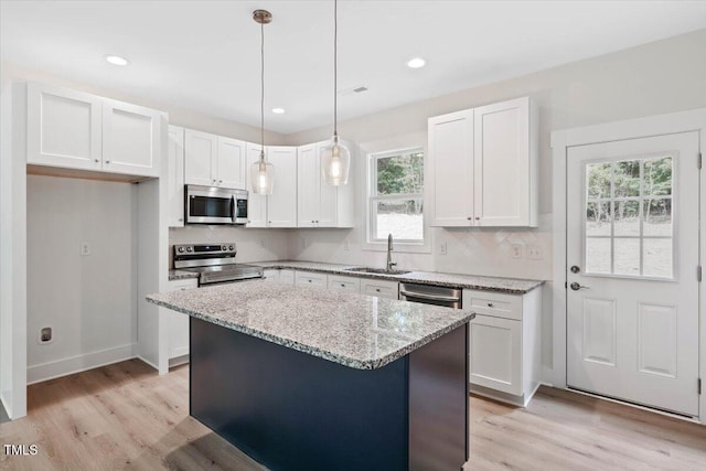 kitchen with stainless steel appliances, a sink, light wood finished floors, white cabinetry, and recessed lighting