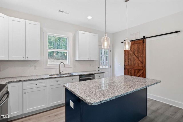 kitchen featuring a sink, light wood-style floors, a kitchen island, white cabinetry, and recessed lighting