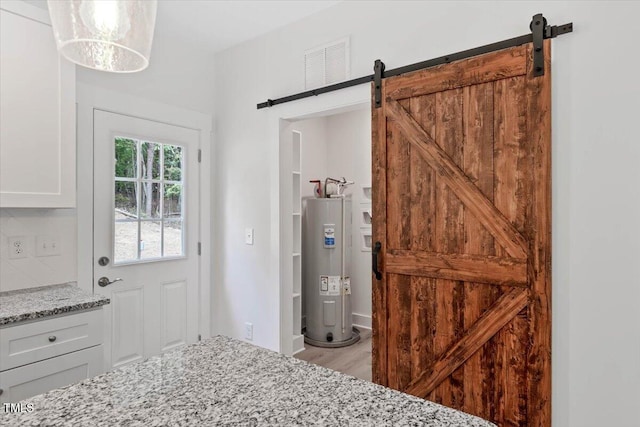 doorway featuring a barn door, electric water heater, and wood finished floors