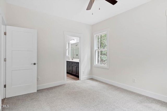 unfurnished bedroom featuring carpet floors, baseboards, a sink, connected bathroom, and ceiling fan