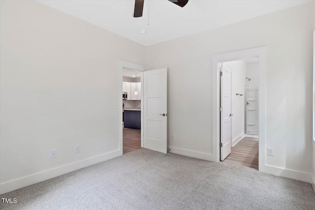 unfurnished bedroom with carpet, baseboards, ensuite bathroom, and a ceiling fan