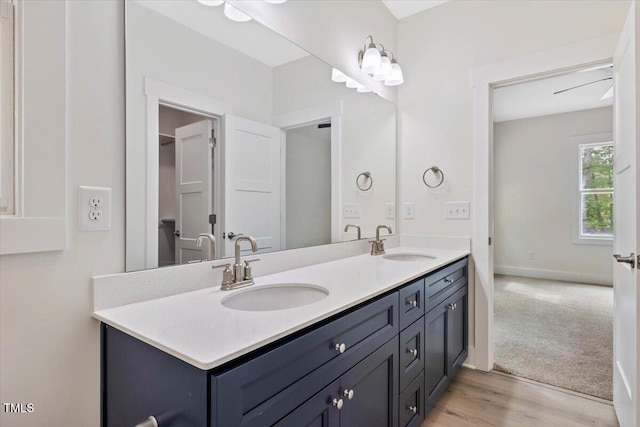 bathroom featuring double vanity, wood finished floors, and baseboards
