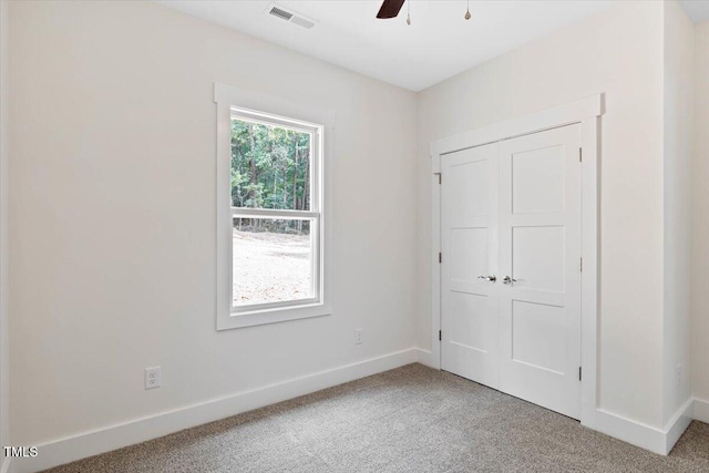 unfurnished bedroom featuring light colored carpet, baseboards, a closet, and ceiling fan