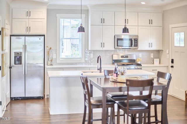 941 W Club Blvd, Durham, NC 27701 - kitchen with stainless steel appliances, light countertops, crown molding, dark wood finished floors, and a center island with sink