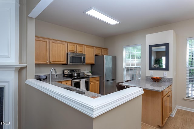 7244 Galon Glen Rd, Raleigh, NC 27613 - kitchen with stainless steel appliances, a peninsula, light wood finished floors, and plenty of natural light